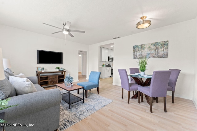 living area with light wood-style floors, ceiling fan, and baseboards