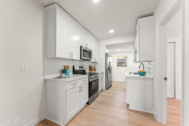 kitchen with stainless steel appliances, decorative backsplash, light countertops, light wood-style flooring, and recessed lighting