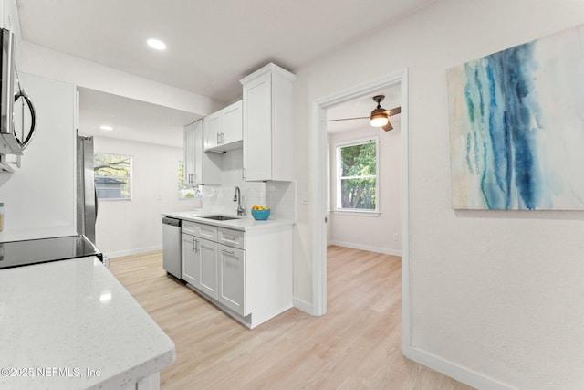 kitchen with a sink, appliances with stainless steel finishes, light wood-type flooring, baseboards, and recessed lighting