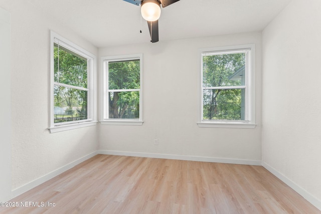 empty room with plenty of natural light, ceiling fan, light wood finished floors, and baseboards