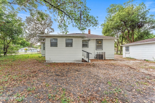 back of property with central air condition unit, a chimney, and fence