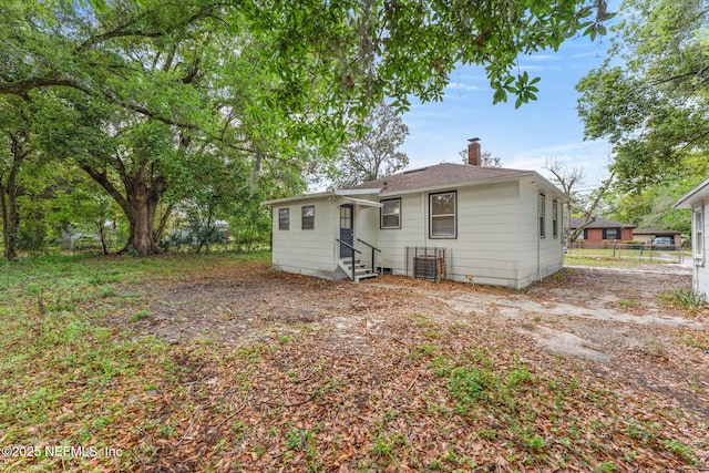 back of property with entry steps, a chimney, and fence