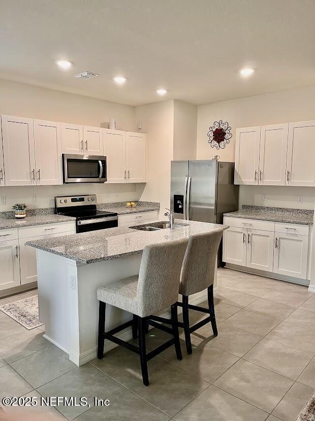 172 Reena Dr, Daytona Beach, FL 32117 - kitchen with appliances with stainless steel finishes, a sink, a breakfast bar area, white cabinets, and recessed lighting