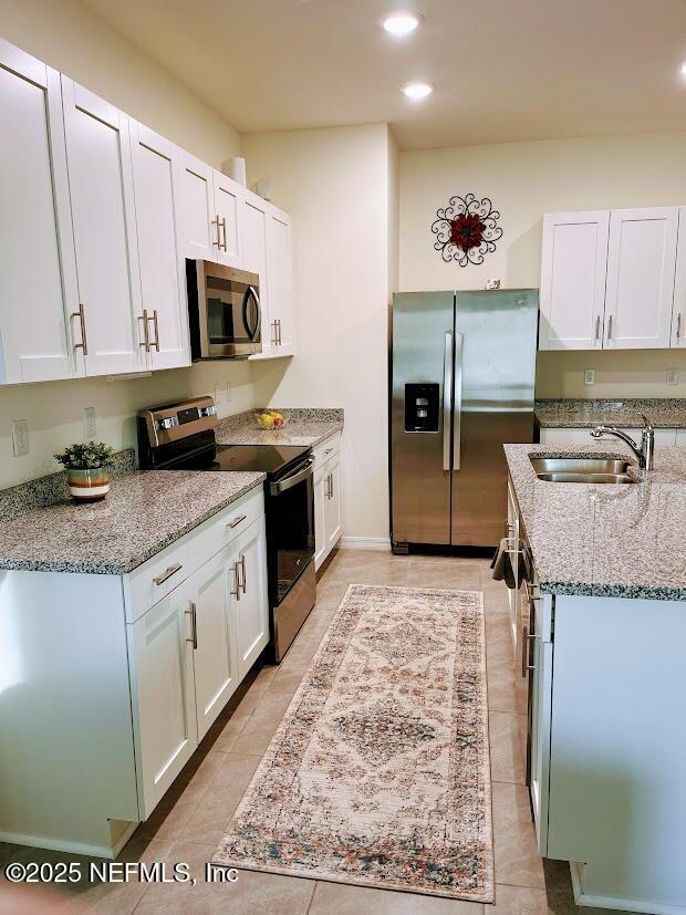 172 Reena Dr, Daytona Beach, FL 32117 - kitchen with stainless steel appliances, a sink, light stone counters, white cabinets, and recessed lighting
