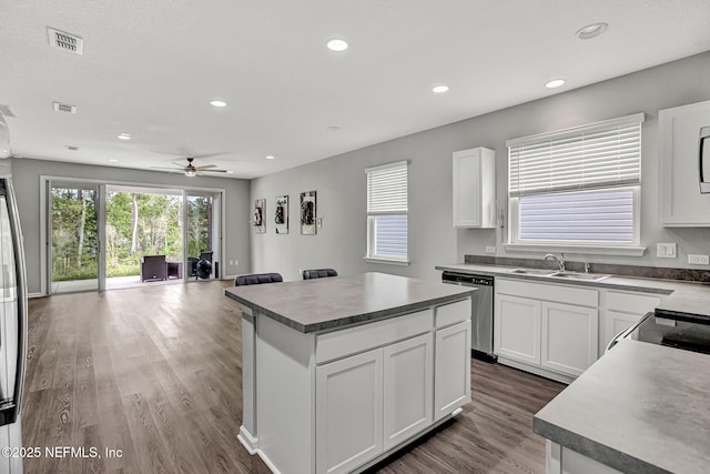 1860 Cogdill, Middleburg, FL 32068 - kitchen with stainless steel dishwasher, a sink, a kitchen island, wood finished floors, and white cabinetry
