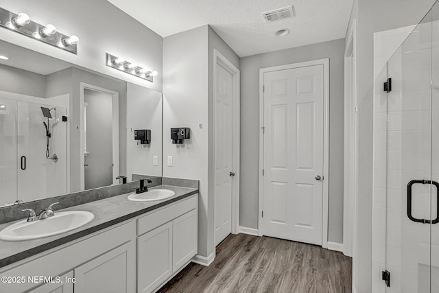 1860 Cogdill, Middleburg, FL 32068 - bathroom featuring a stall shower, wood finished floors, double vanity, a textured ceiling, and baseboards
