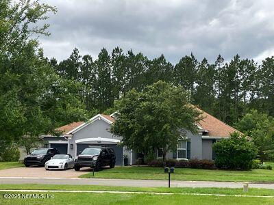 view of property hidden behind natural elements with a front yard, an attached garage, and concrete driveway