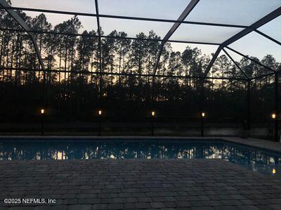 outdoor pool with glass enclosure and a patio