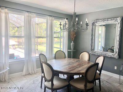 dining area with a chandelier, plenty of natural light, baseboards, and a textured ceiling