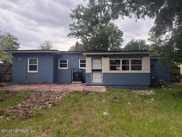 7205 Linda Dr, Jacksonville, FL 32208 - rear view of property featuring fence, a chimney, and stucco siding