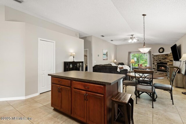 880 W American Eagle Dr, Saint Augustine, FL 32092 - kitchen featuring dark countertops, open floor plan, ceiling fan, a fireplace, and light tile patterned floors