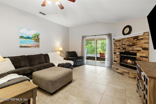 880 W American Eagle Dr, Saint Augustine, FL 32092 - living room featuring a ceiling fan, vaulted ceiling, light tile patterned floors, a stone fireplace, and a textured ceiling