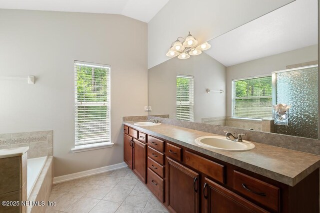 880 W American Eagle Dr, Saint Augustine, FL 32092 - bathroom with vaulted ceiling, double vanity, baseboards, a bath, and tile patterned flooring