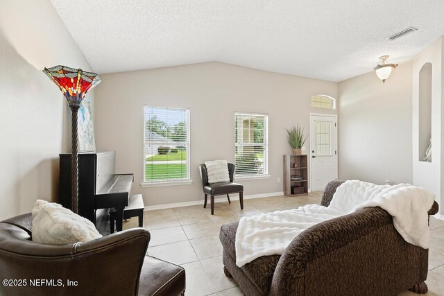 880 W American Eagle Dr, Saint Augustine, FL 32092 - living area with light tile patterned flooring, lofted ceiling, a textured ceiling, arched walkways, and baseboards