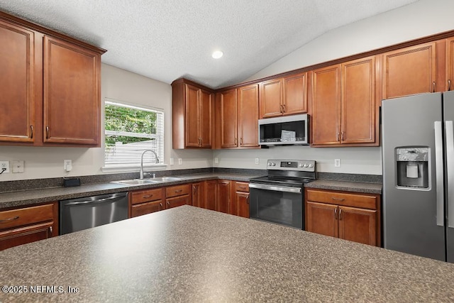 880 W American Eagle Dr, Saint Augustine, FL 32092 - kitchen with appliances with stainless steel finishes, a sink, dark countertops, vaulted ceiling, and a textured ceiling