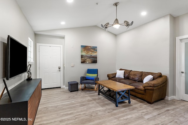 living area featuring lofted ceiling, light wood-style floors, a chandelier, and baseboards