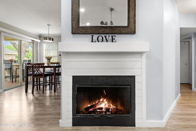 detailed view of a tile fireplace, wood finished floors, baseboards, and ornamental molding