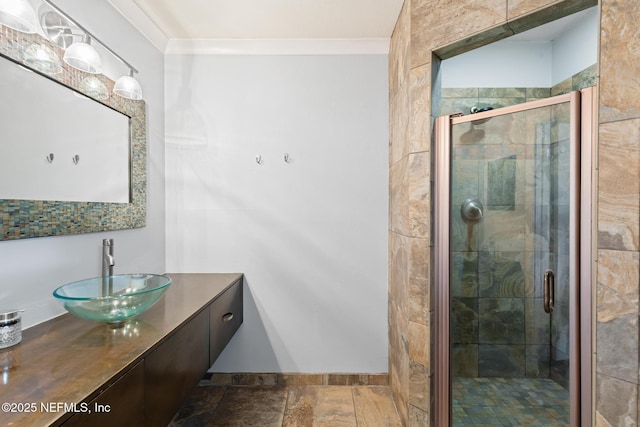 full bath featuring a stall shower, vanity, crown molding, and stone tile floors