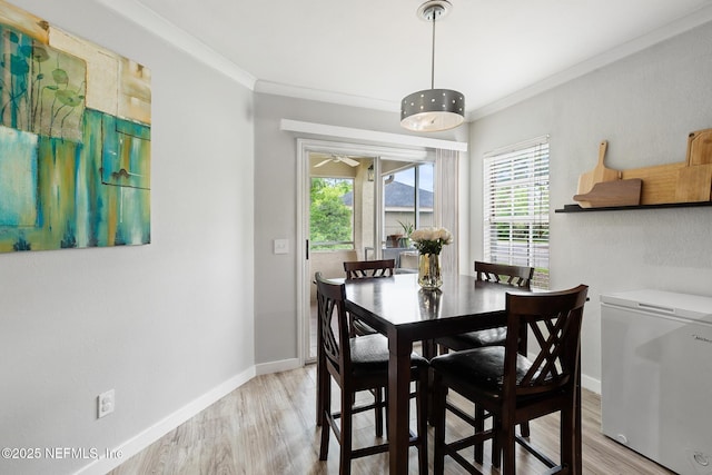 dining area featuring light wood-style floors, ornamental molding, baseboards, and ceiling fan