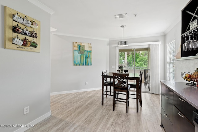 dining room with ornamental molding, light wood finished floors, and baseboards