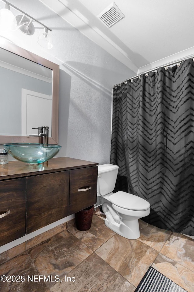 full bathroom with toilet, vanity, ornamental molding, curtained shower, and a textured wall