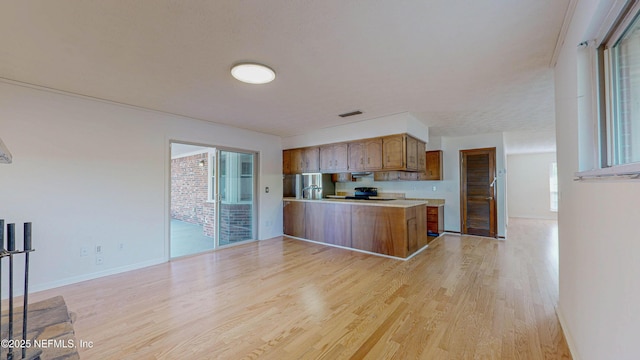 kitchen with light wood-style floors, a peninsula, light countertops, brown cabinets, and baseboards