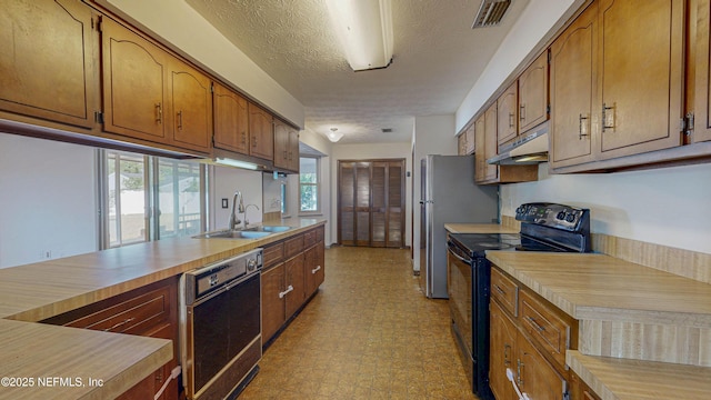 kitchen with black appliances, a sink, under cabinet range hood, light floors, and light countertops