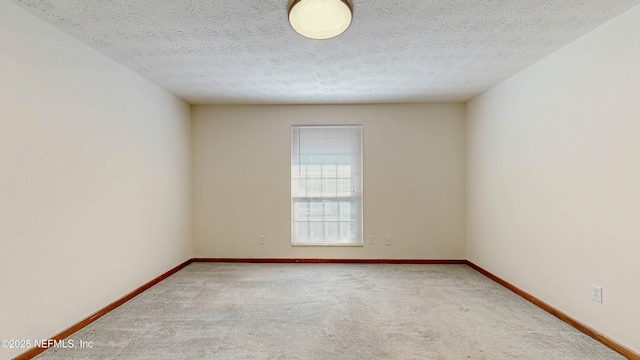 carpeted empty room featuring baseboards and a textured ceiling