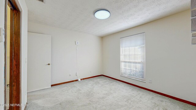 carpeted empty room with baseboards and a textured ceiling