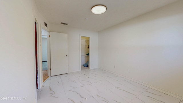 empty room featuring light marble finish flooring and baseboards