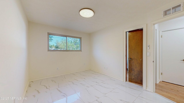unfurnished room featuring light marble finish flooring and baseboards