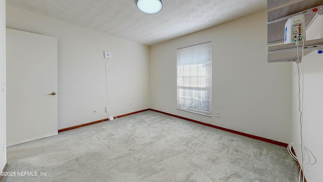 spare room with carpet floors, baseboards, and a textured ceiling