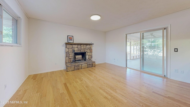 unfurnished living room featuring wood finished floors, healthy amount of natural light, a fireplace, and baseboards
