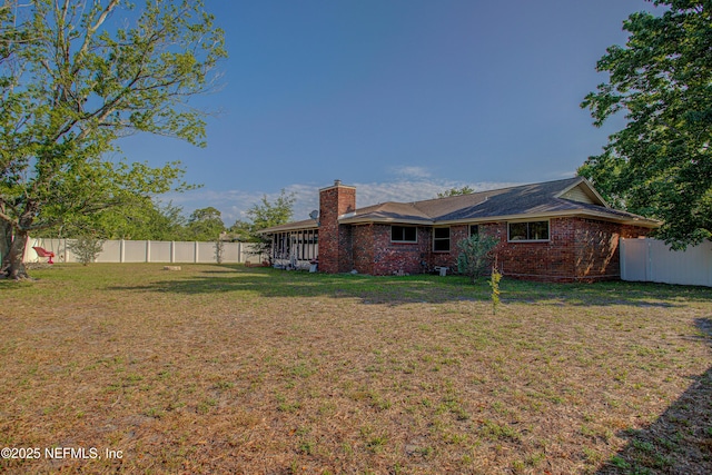 back of house featuring a chimney, brick siding, and a sunroom