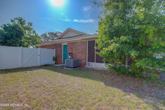 rear view of property featuring a gate, brick siding, and central air condition unit