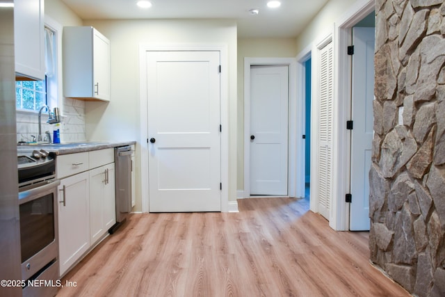 kitchen featuring appliances with stainless steel finishes, light wood-type flooring, white cabinetry, recessed lighting, and a sink