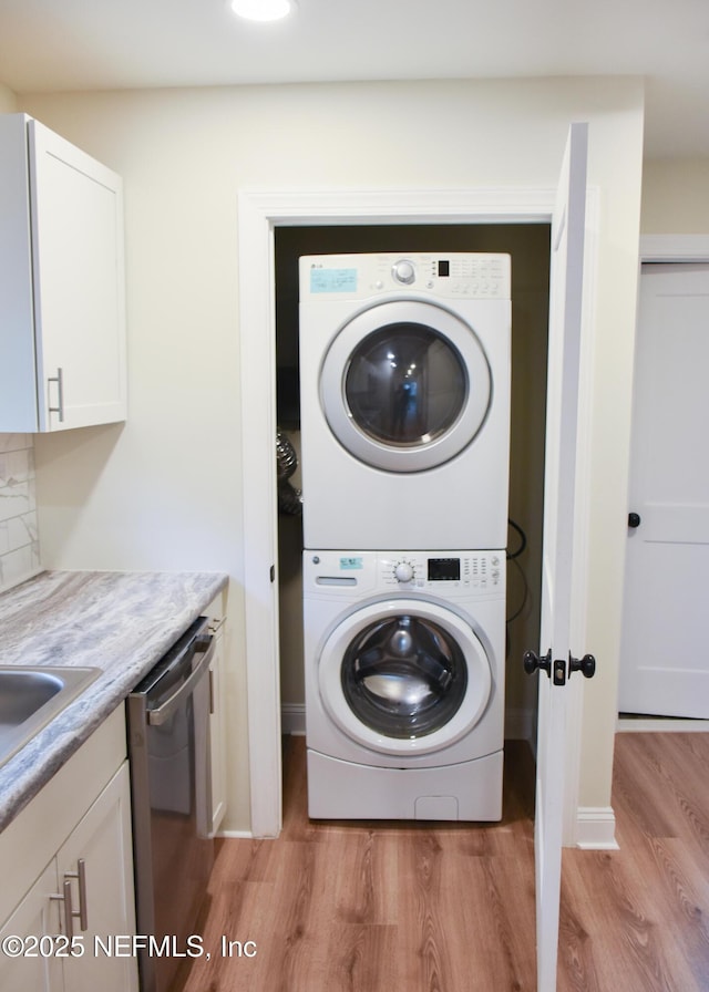 laundry room with stacked washer / drying machine and light wood-type flooring