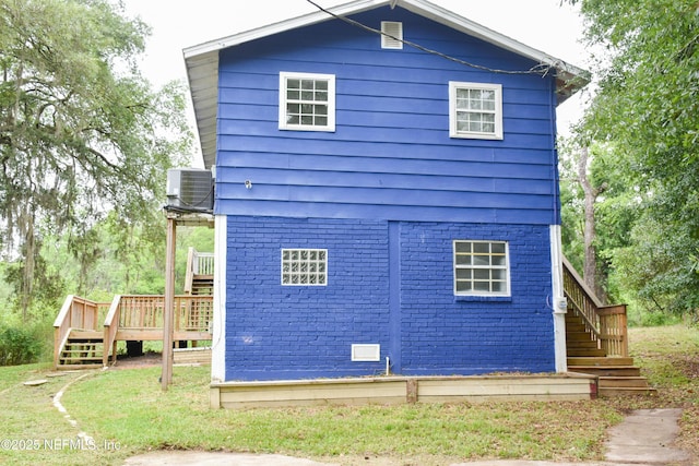 view of property exterior with stairway, a deck, central AC, and brick siding