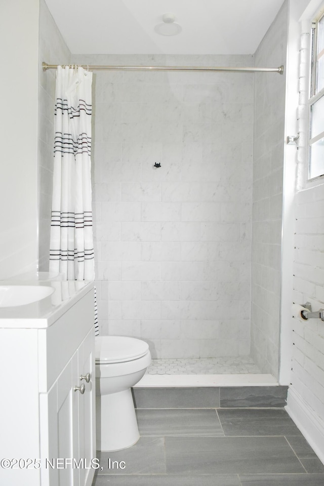 bathroom featuring a tile shower, toilet, and vanity