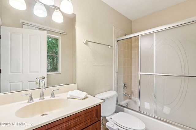 bathroom with vanity, toilet, and combined bath / shower with glass door
