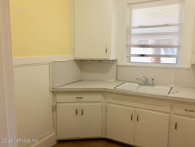 2523 Forbes St, Jacksonville, FL 32204 - kitchen featuring light countertops, a sink, wainscoting, and white cabinets