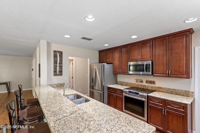 7013 Elfo Rd, Keystone Heights, FL 32656 - kitchen with appliances with stainless steel finishes, a sink, a breakfast bar area, light stone counters, and recessed lighting