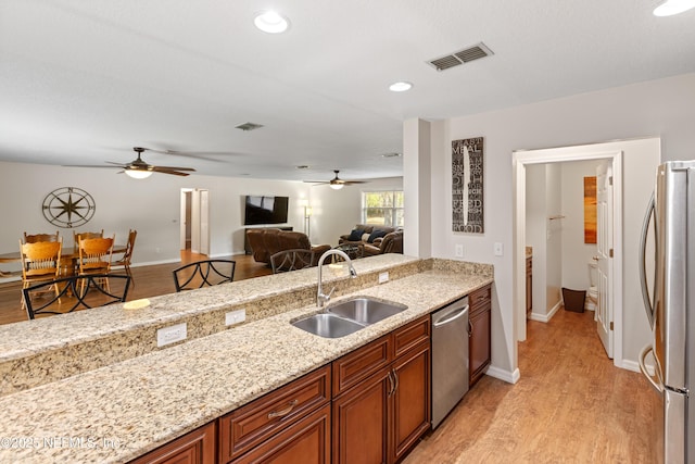 7013 Elfo Rd, Keystone Heights, FL 32656 - kitchen featuring appliances with stainless steel finishes, a sink, a ceiling fan, light wood finished floors, and light stone counters