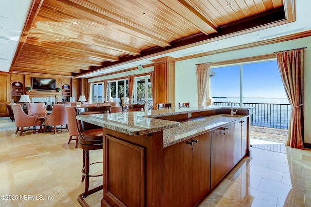 2358 Riverside Ave Unit 304, Jacksonville, FL 32204 - kitchen with wooden ceiling with exposed beams, brown cabinetry, a kitchen breakfast bar, light stone countertops, and a sink