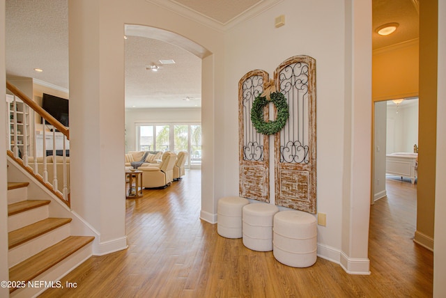 9155 June Ln, Saint Augustine Beach, FL 32080 - foyer featuring arched walkways, wood finished floors, stairs, baseboards, and crown molding