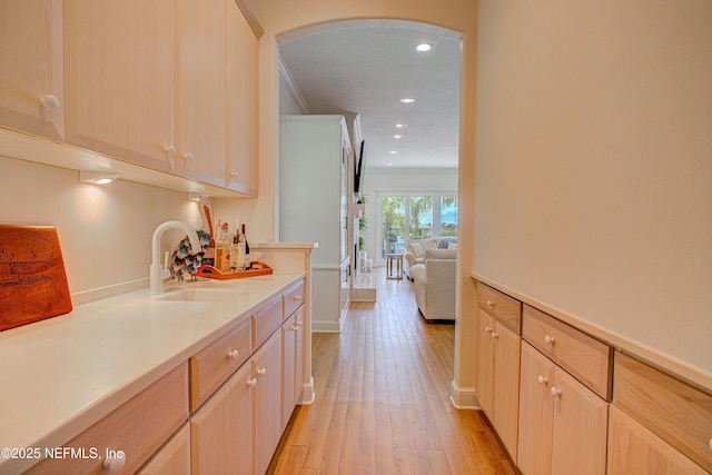 9155 June Ln, Saint Augustine Beach, FL 32080 - kitchen featuring a sink, arched walkways, light wood-style floors, crown molding, and recessed lighting