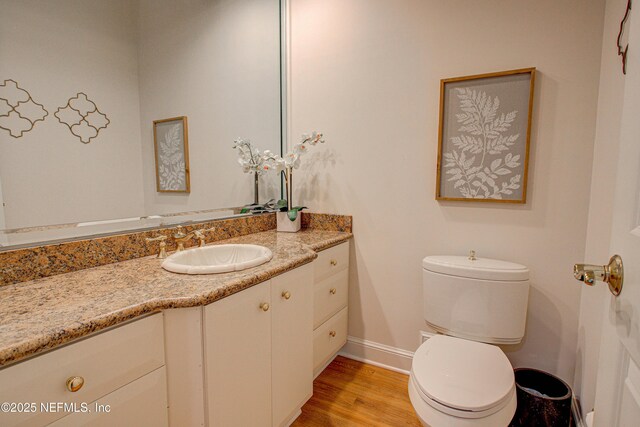 9155 June Ln, Saint Augustine Beach, FL 32080 - half bathroom with baseboards, toilet, vanity, and wood finished floors
