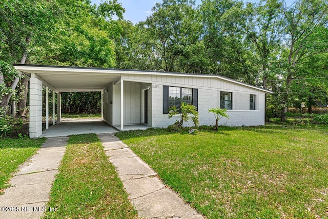 view of front of house featuring driveway, a carport, a front lawn, and concrete block siding