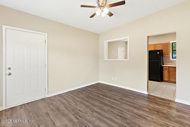 empty room featuring a ceiling fan, light wood-type flooring, and baseboards