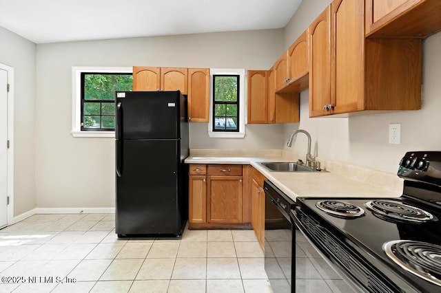 kitchen featuring black appliances, a sink, plenty of natural light, and light countertops